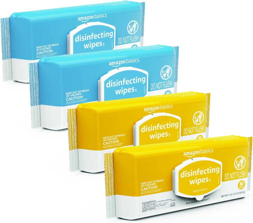 Four packs of Amazon Basics disinfecting wipes, two in blue packaging and two in yellow, are arranged in a row. The packs display Do Not Flush and Lemon Scent on the yellow ones.