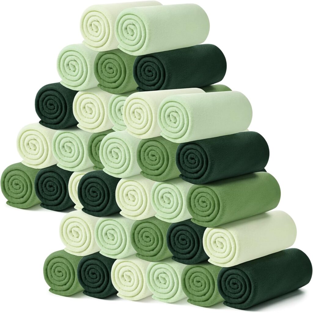 A pyramid-like stack of rolled towels in varying shades of green and cream arranged neatly in rows on a white background.